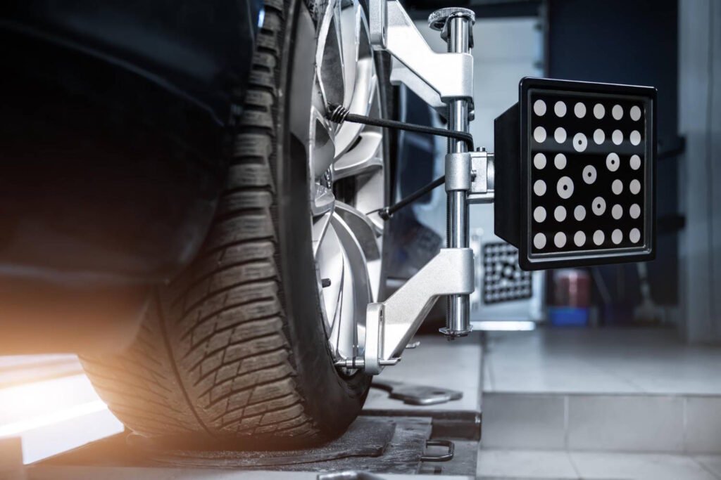 Close-up view of a car tire being aligned using modern wheel alignment and balancing equipment at an auto repair shop. 