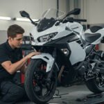 A mechanic performing maintenance on a Kawasaki Ninja 400 in a professional workshop. The bike is on a lift, surrounded by tools and equipment.